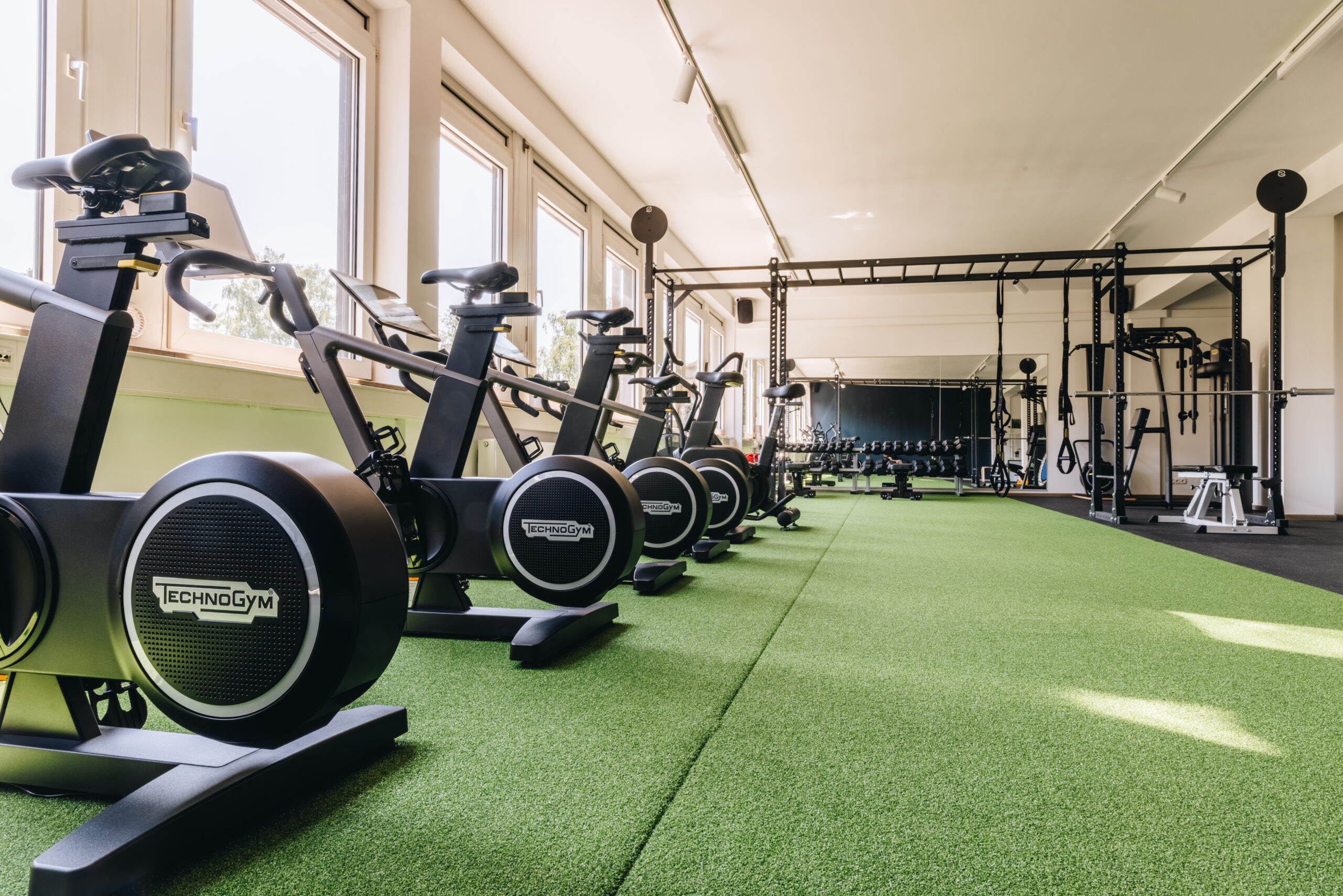 Sportstudio Norderstedt Cardio Der Cardio Bereich mit den Fahrrädern und Cross-Trainern, sowie im Hintergrund das Rack und der Hantelbereich mit Spiegel.